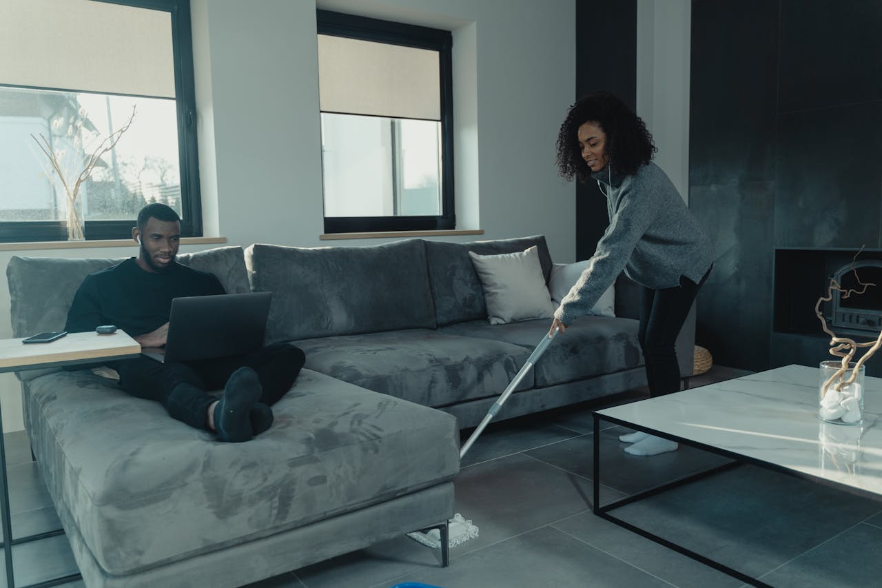 Couple sharing household chores in a stylish living room, blending comfort and cooperation.